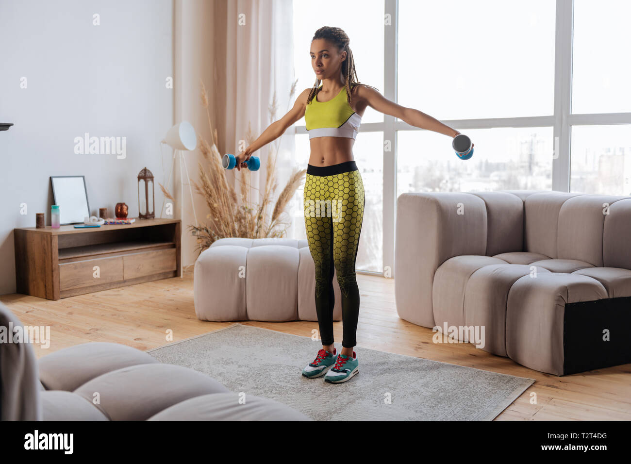 Leggings jaune vif. Mince et fit woman wearing leggings jaune vif et haut de faire les exercices avec haltères longues Banque D'Images