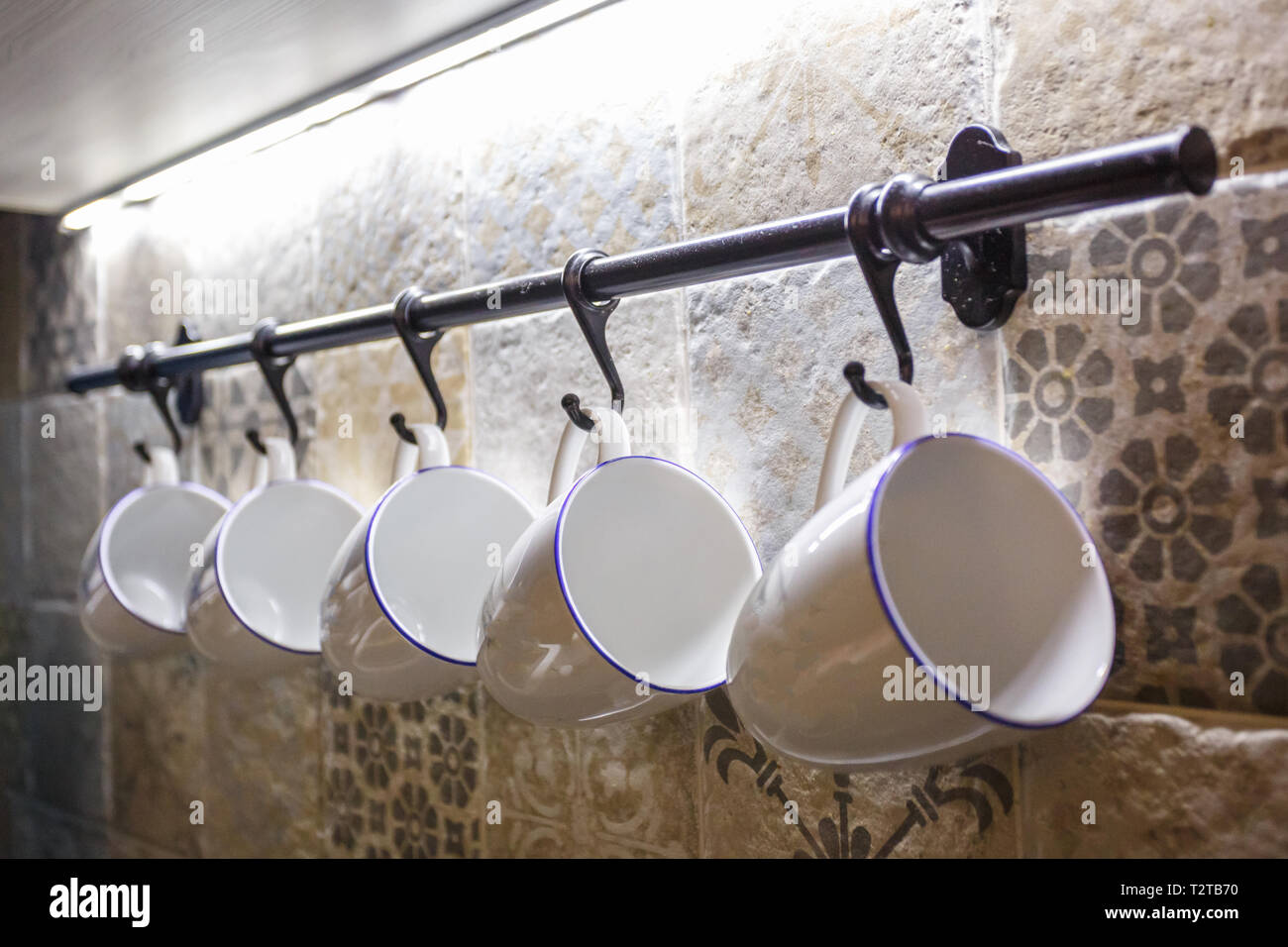 Tasses blanc céramique accroché sur des crochets dans la cuisine Banque D'Images
