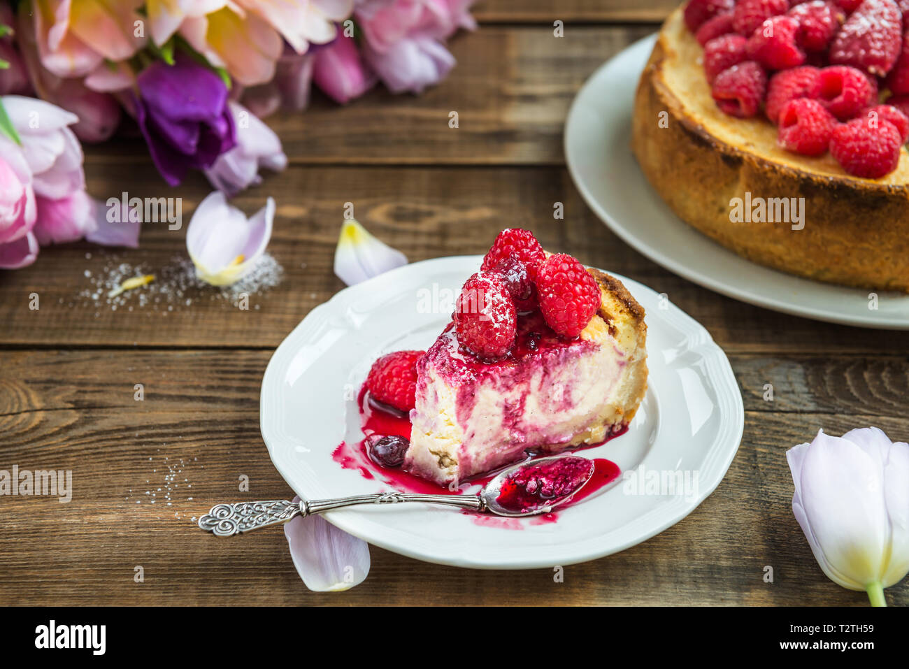 Tranche de gâteau à la vanille avec les framboises et sauce aux baies sur fond rustique foncé Banque D'Images