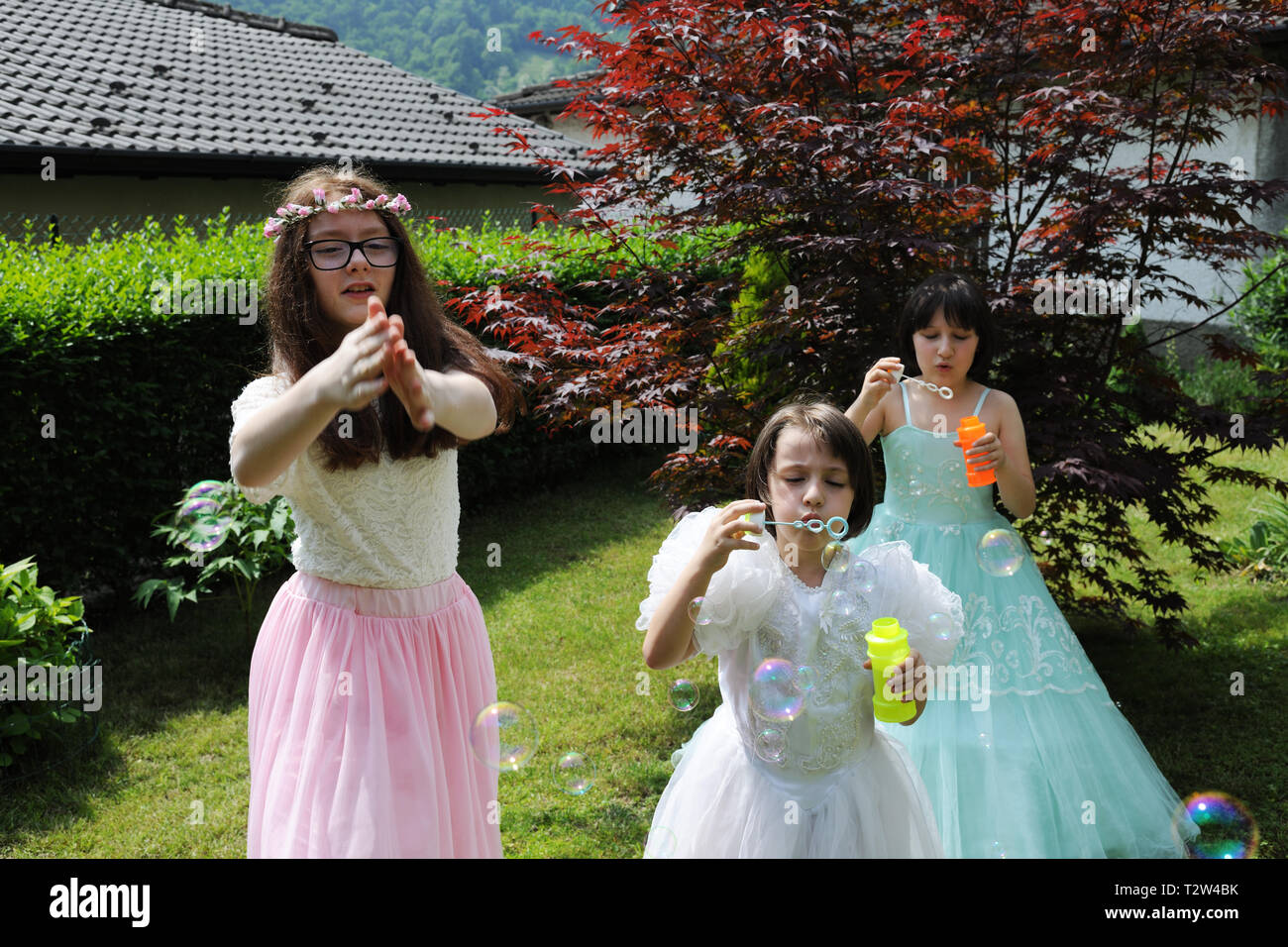 Les petites filles vêtues comme des princesses jouant dans le jardin avec des bulles Banque D'Images