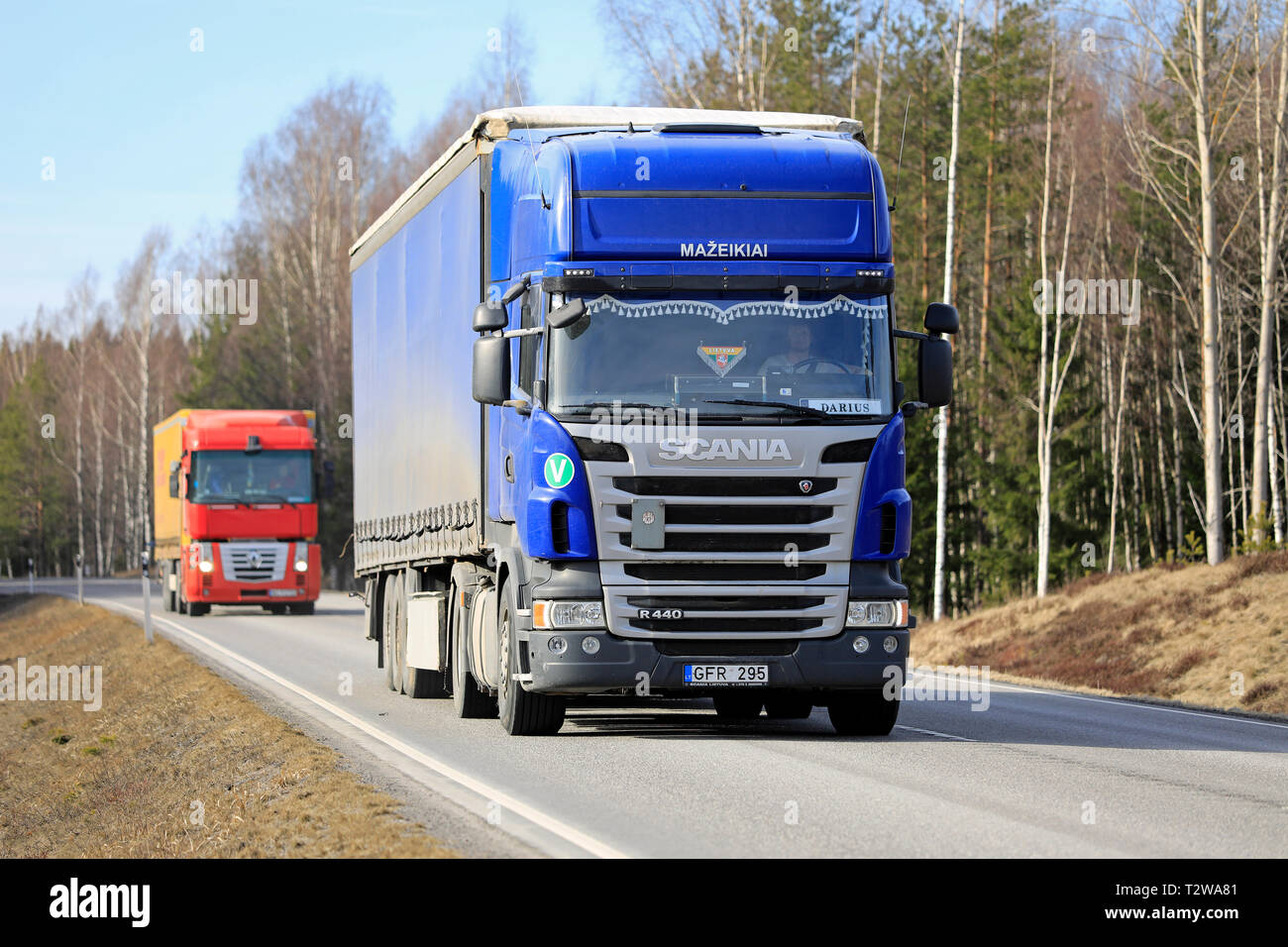 Tenhola, Finlande - le 29 mars 2019 : Deux camions de fret, Scania R440 bleu et rouge Renault Magnum transporter les marchandises le long d'une route de campagne pour un jour de printemps. Banque D'Images