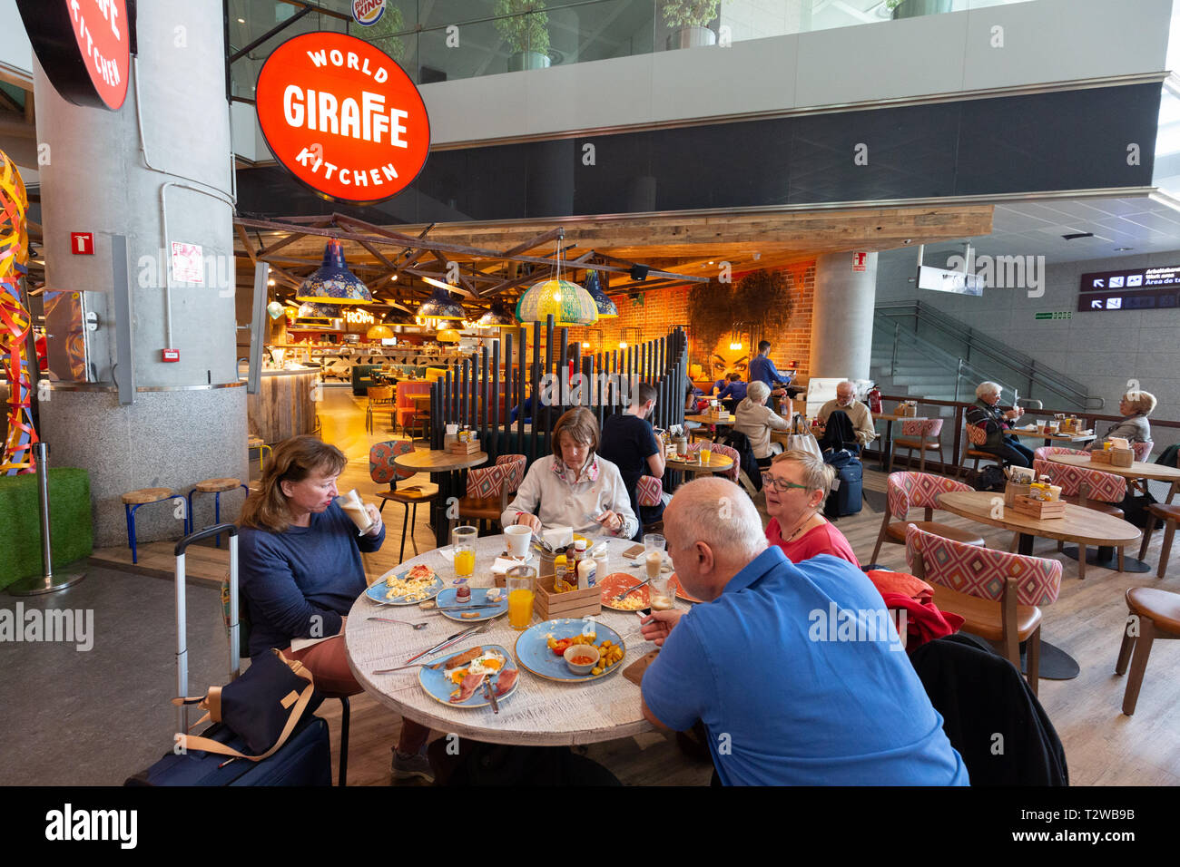Les gens à manger cuisine monde girafe, terminal intérieur, de départs, de l'aéroport de Malaga, Malaga Espagne Europe Banque D'Images