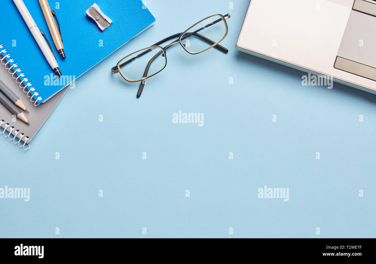 Sur un fond bleu, l'ordinateur portable de verres et les fournitures de bureau. Image fournitures scolaires et matériel de bureau Banque D'Images