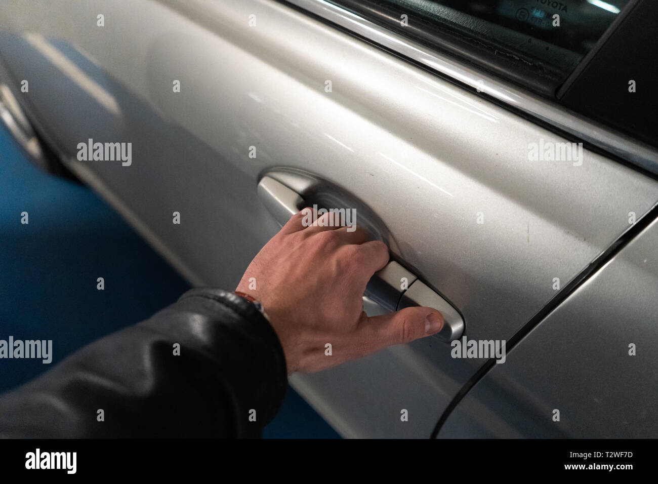 Un gros plan de la main des hommes sur le loquet d'une porte de la voiture  l'ouverture - Lumière-couleur voiture - veste en cuir noir Photo Stock -  Alamy