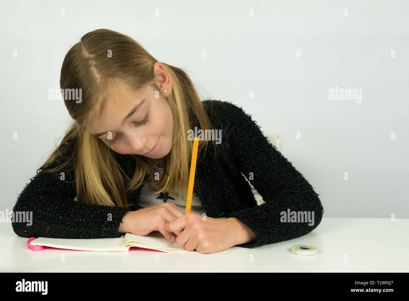 Portrait d'une jolie fille est écrit sur son papier, faire ses devoirs Banque D'Images