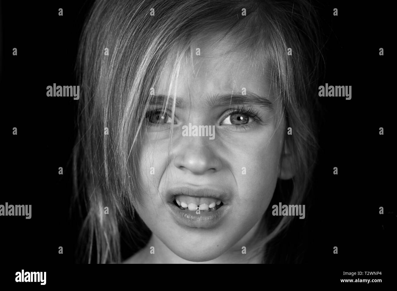 Portrait d'une jeune fille, montre dégoûté de l'émotion sur un fond noir en noir et blanc Banque D'Images