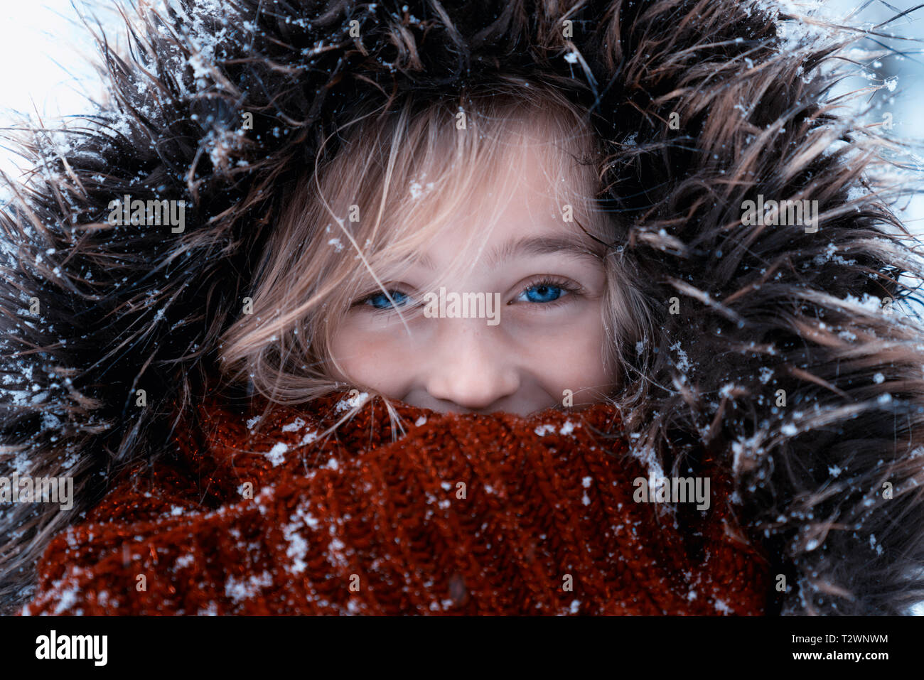 Portrait d'une jolie fille avec de beaux yeux bleus sur un froid jour de neige en hiver. Elle est habillée dans des vêtements chauds Banque D'Images