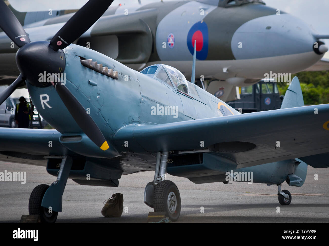 L'emblématique britannique de la DEUXIÈME GUERRE MONDIALE avion de chasse Spitfire sur le sol avec un Avro Vulcan bomber dans l'arrière-plan. Banque D'Images