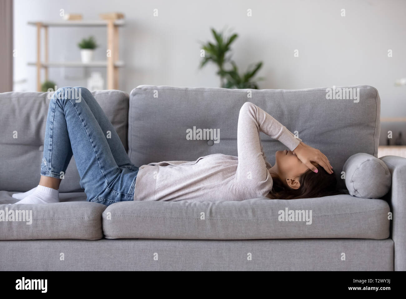 Longueur complète young woman lying on couch souffre de chagrin Banque D'Images