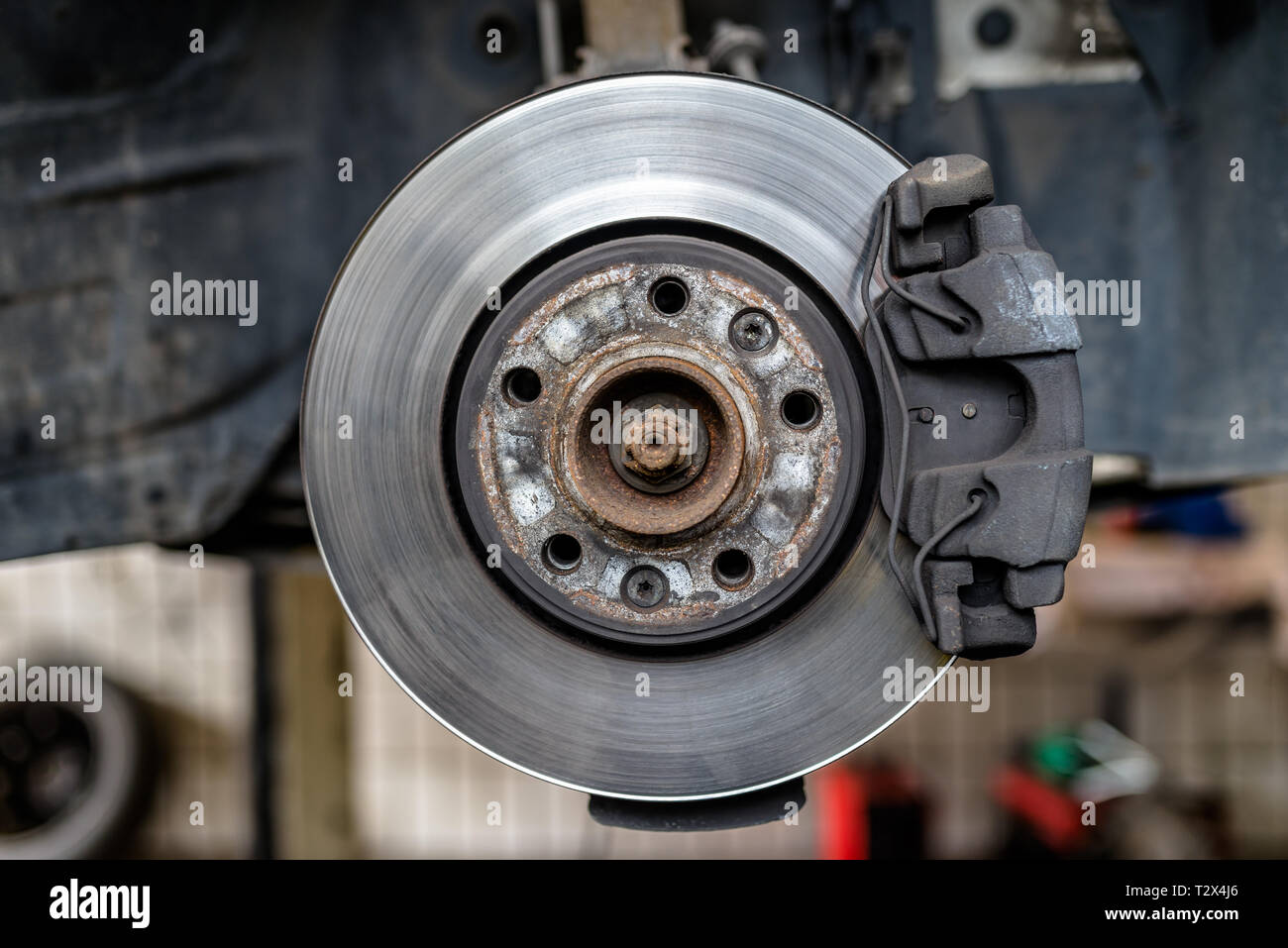 Disques de frein avant avec les plaquettes de frein et d'étrier dans la  voiture, sur une voiture ascenseur dans un atelier Photo Stock - Alamy