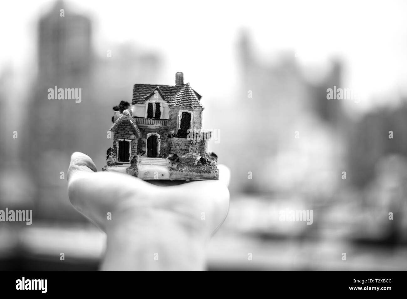 Maison Miniature sur une main avec NYC skyline en arrière-plan Banque D'Images