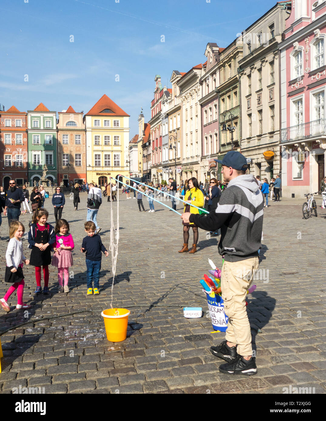 Les jeunes enfants, garçons et filles de regarder un spectacle de rue dans les ruelles pavées de la vieille ville dans la ville polonaise de Poznan, Pologne Banque D'Images