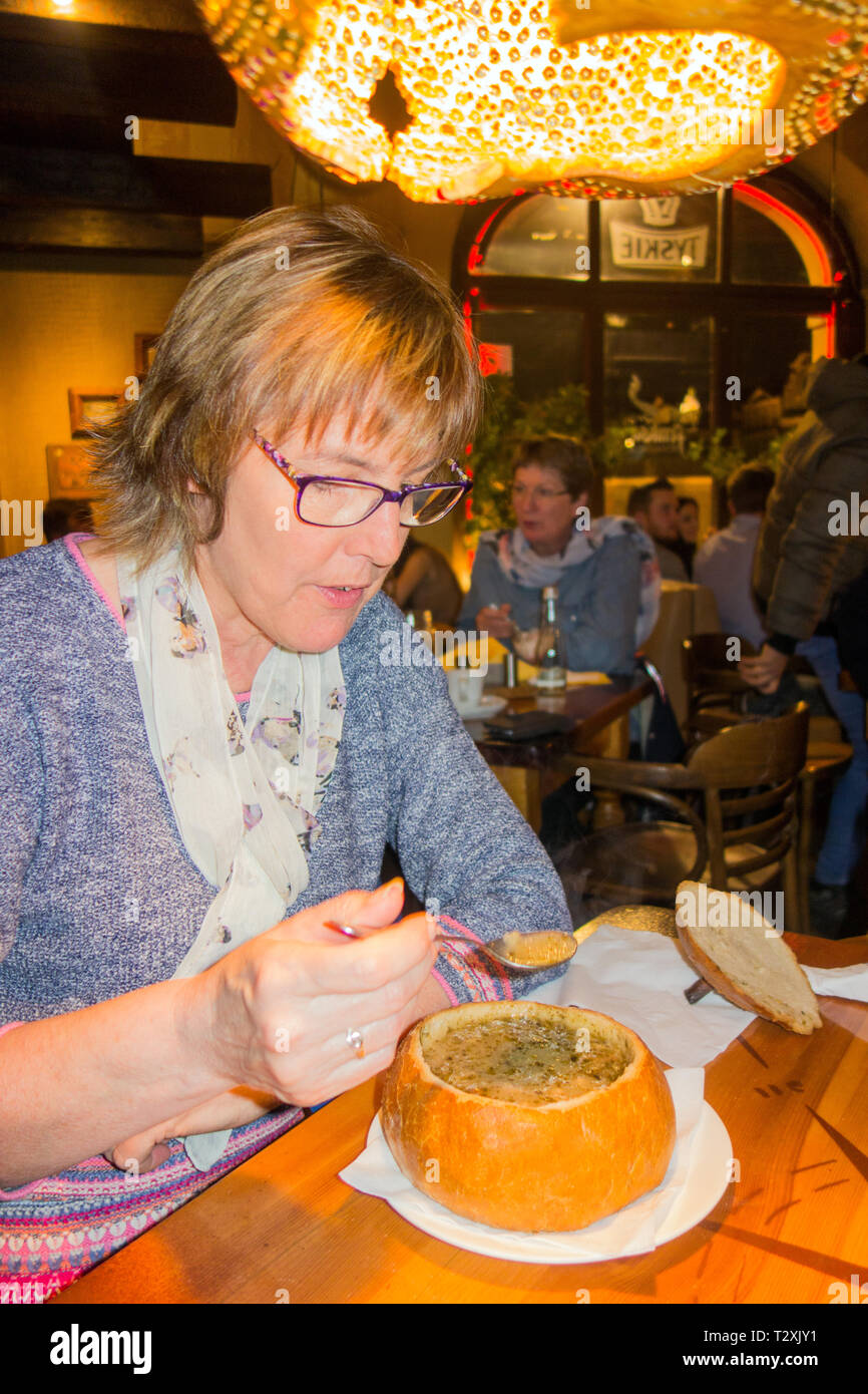 Femme mangeant une soupe Zurek polonais seigle servi dans un bol de pain, dans un restaurant de la ville polonaise de Poznan la Banque D'Images