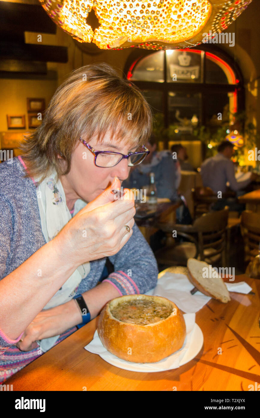 Femme mangeant une soupe Zurek polonais seigle servi dans un bol de pain, dans un restaurant de la ville polonaise de Poznan la Banque D'Images