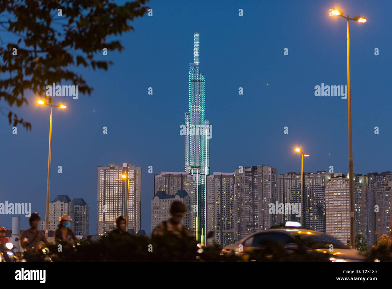 Skyline nuit Vinhomes de Central Park avec ses gratte-ciel 81 avec l'éclairage de rue et de trafic dans l'avant-plan (floue). Banque D'Images