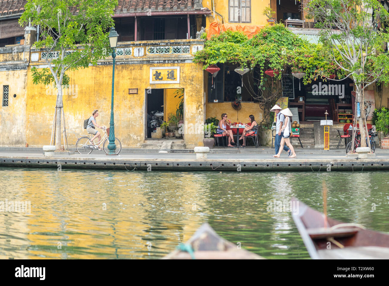 Hoi An, Vietnam - 28 octobre 2018 : la vieille ville riverside avec les voyageurs à vélo, la marche et assis dans un restaurant. Banque D'Images