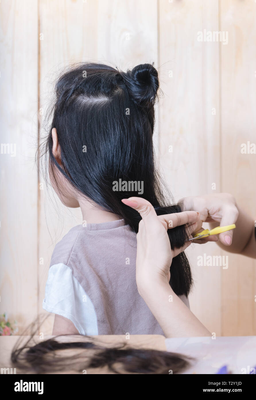 La fille obtient une coupe par sa mère Banque D'Images