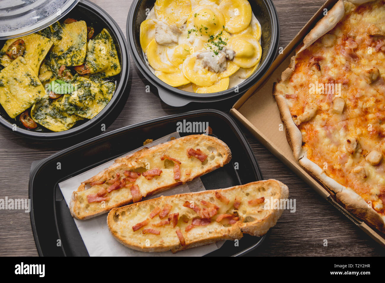 Les pâtes italiennes à emporter de la nourriture. Boîte de pizza avec poivrons verts, pain à l'ail, fetuccine et ravioli sur la boîte en plastique. Cuisine italienne rapide à la maison Banque D'Images