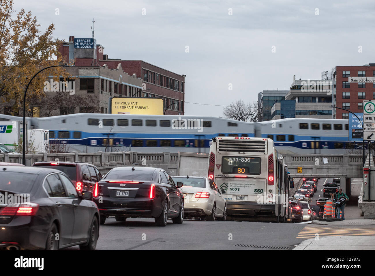 Montréal, Canada - le 9 novembre 2018 : Embouteillage sur le Boulevard St Laurent avec des voitures et un bus alors qu'un train de banlieue de Montréal est Exo Allo passant b Banque D'Images