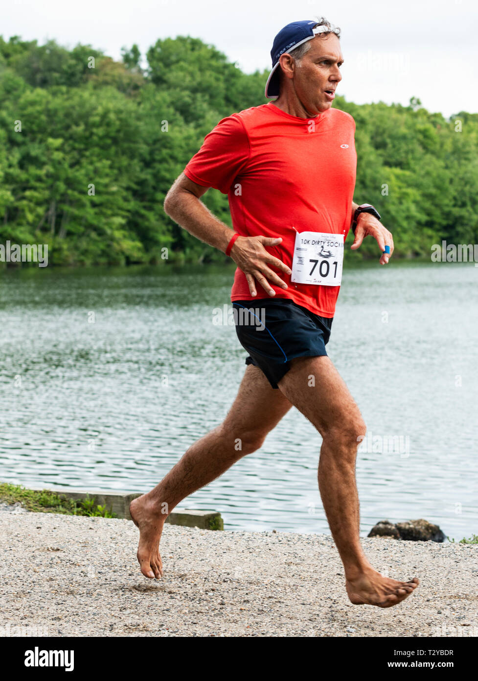 Babylon, New York, USA - 12 août 2018 : Un coureur est l'exécution d'une course de 10 000 mètres avec no shoes on, off road dans les essais en passant un lac au cours de la Di Banque D'Images