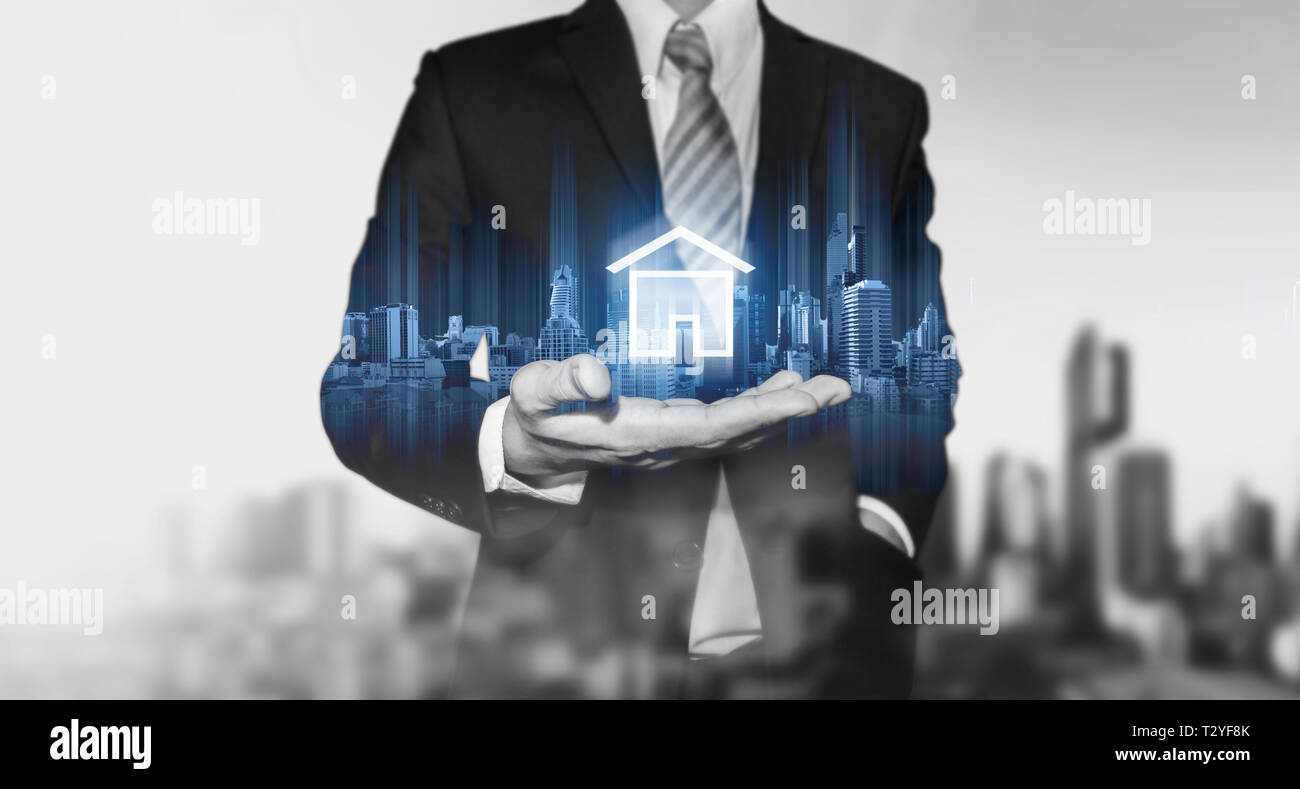 Businessman holding bâtiments modernes, d'hologramme et l'icône d'accueil. De l'immobilier, de la construction et de la technologie smart home concept Banque D'Images