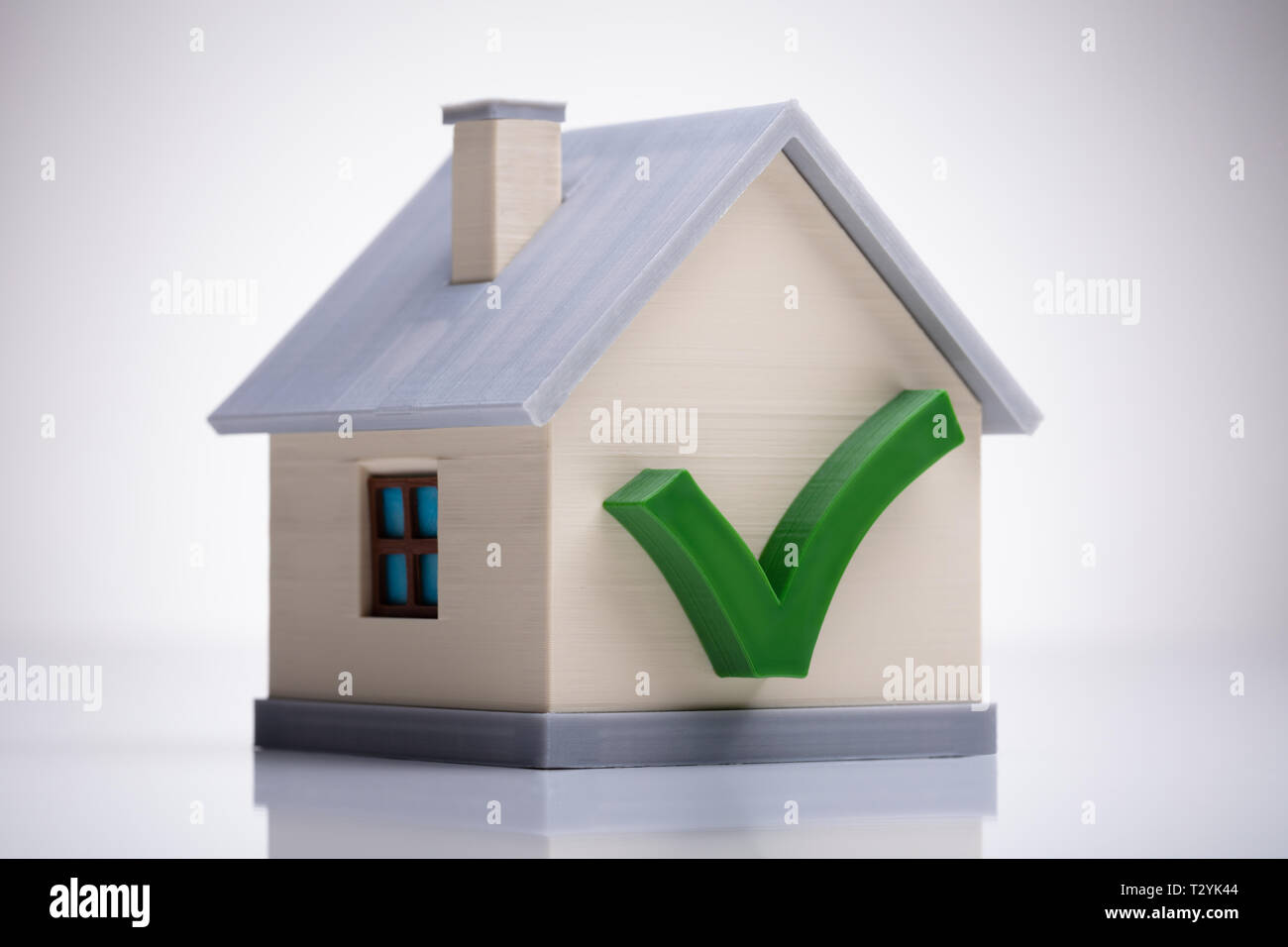 Modèle de maison miniature avec coche verte sur blanc 24 Banque D'Images