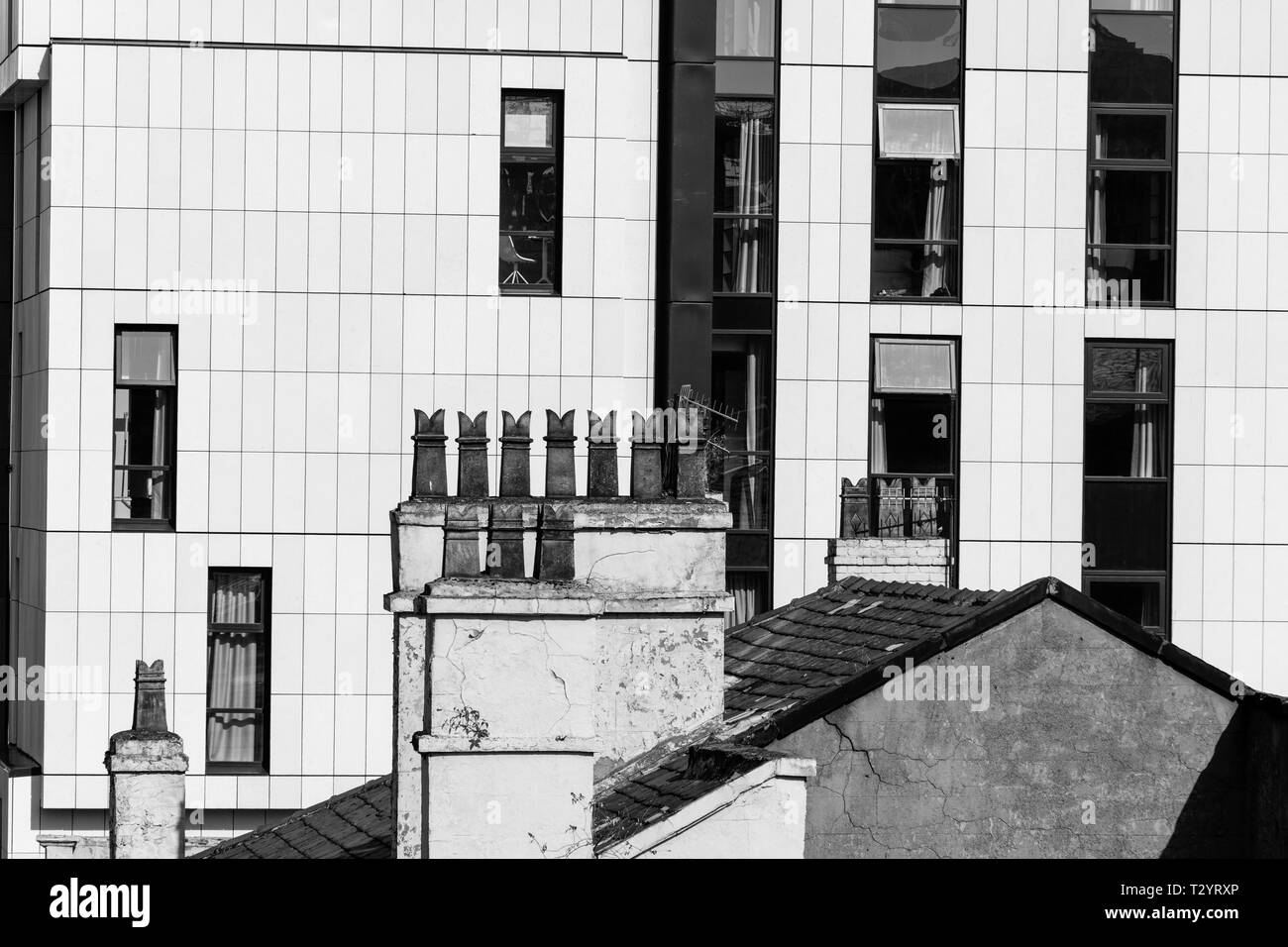 Pots de cheminée sur le toit d'une maison fixé contre le bardage blanc d'un immeuble de bureaux Banque D'Images