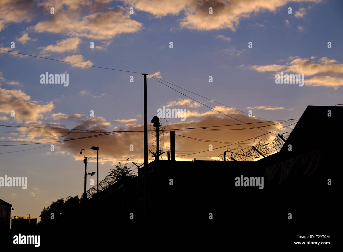 Caméra de surveillance ad barbelés silhouetté contre crépuscule nuages dans une zone industrielle de Sheffield Banque D'Images