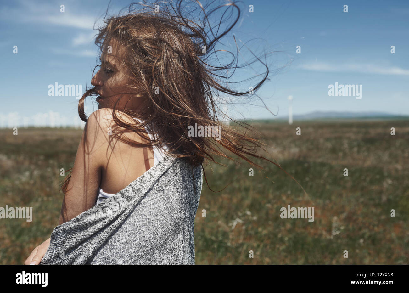 Femme aux longs cheveux ébouriffés à côté de l'éolienne avec le vent Banque D'Images