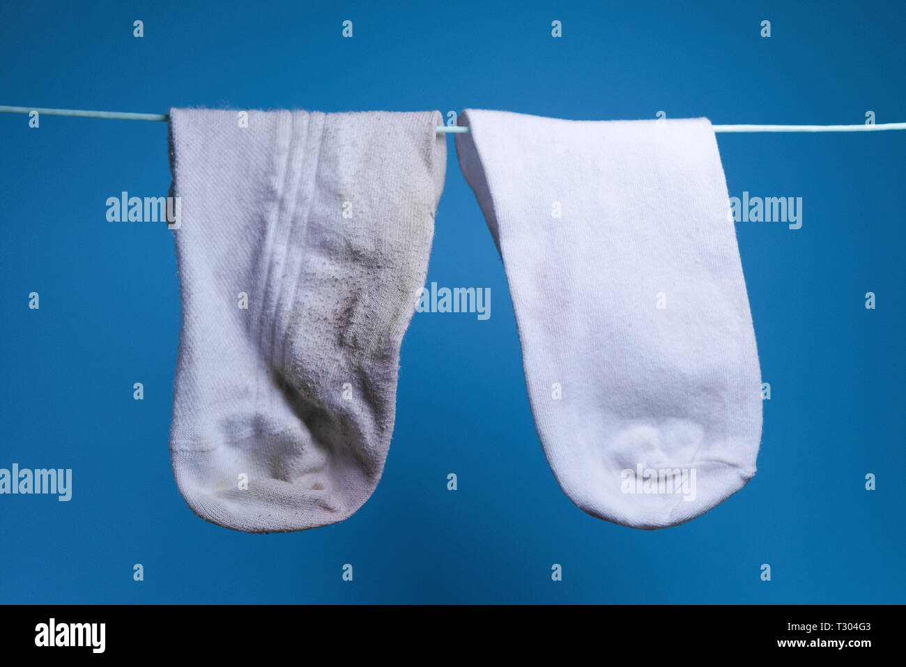 Nettoyer nouvelle chaussette blanche et à côté de la vieille chaussette  sale concept pèse. buanderie. le nettoyage. fond bleu Photo Stock - Alamy