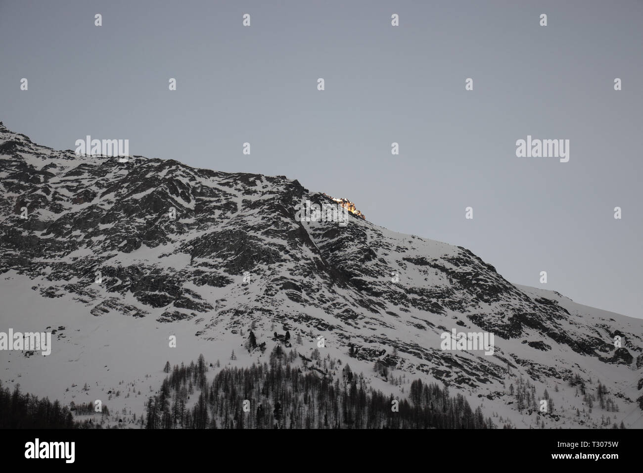 Derniers rayons de soleil illuminent les montagnes couvertes de neige au soir Banque D'Images