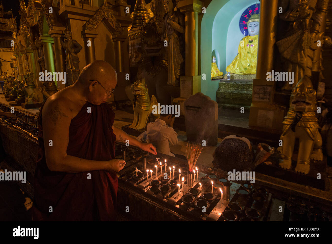 Moine bouddhiste birman lampes à huile de l'éclairage à la pagode Shwedagon, Yangon, Myanmar (Birmanie) Banque D'Images