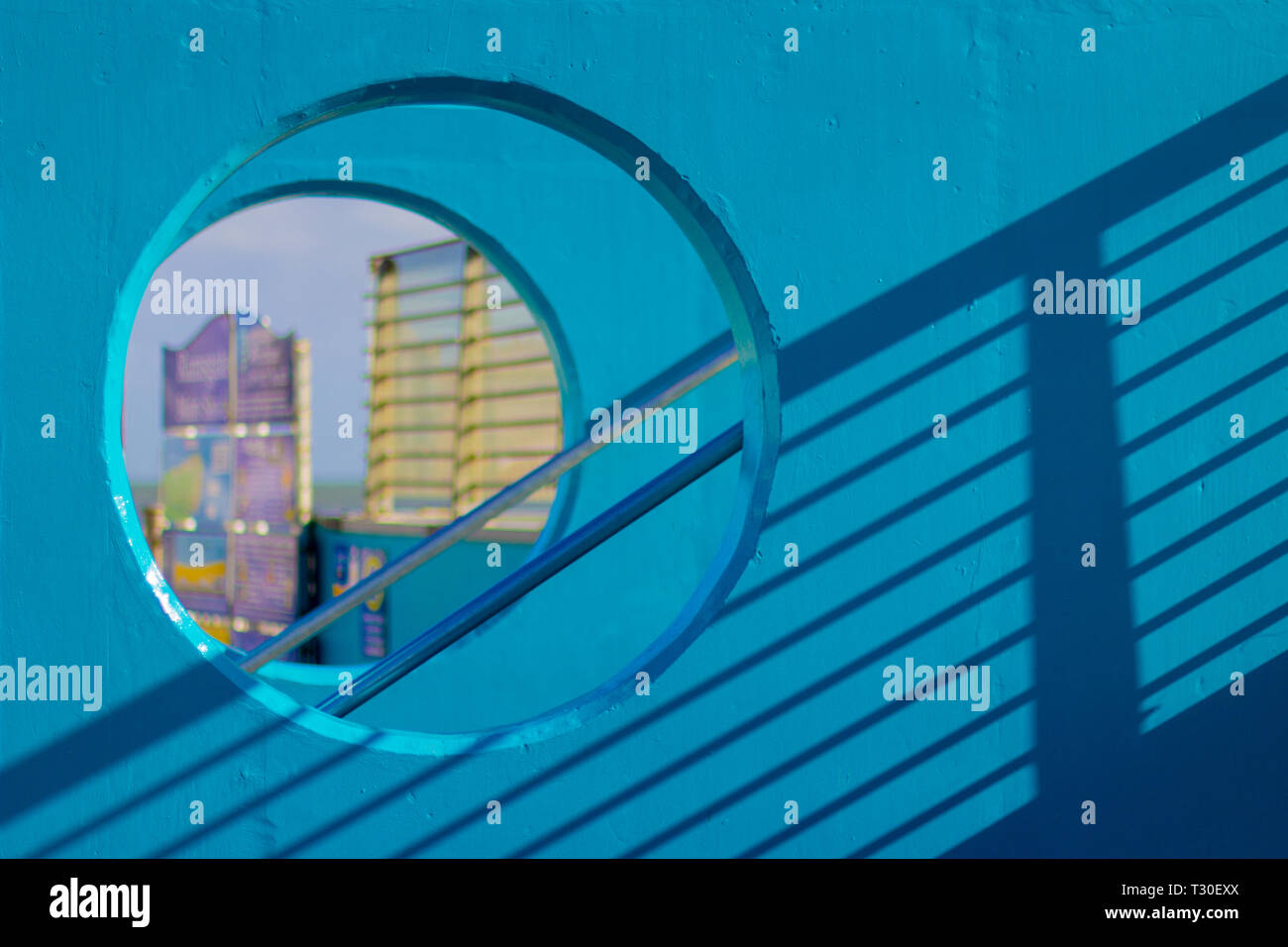 Une Sarcelle de couleur vive le mur avec une fenêtre ronde a une ombre d'un garde-corps métallique Banque D'Images