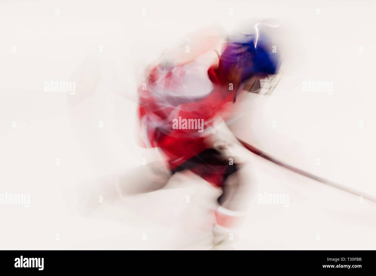 Le joueur de hockey en robe rouge et casque bleu en mouvement, mouvement floue sur stade de glace Banque D'Images