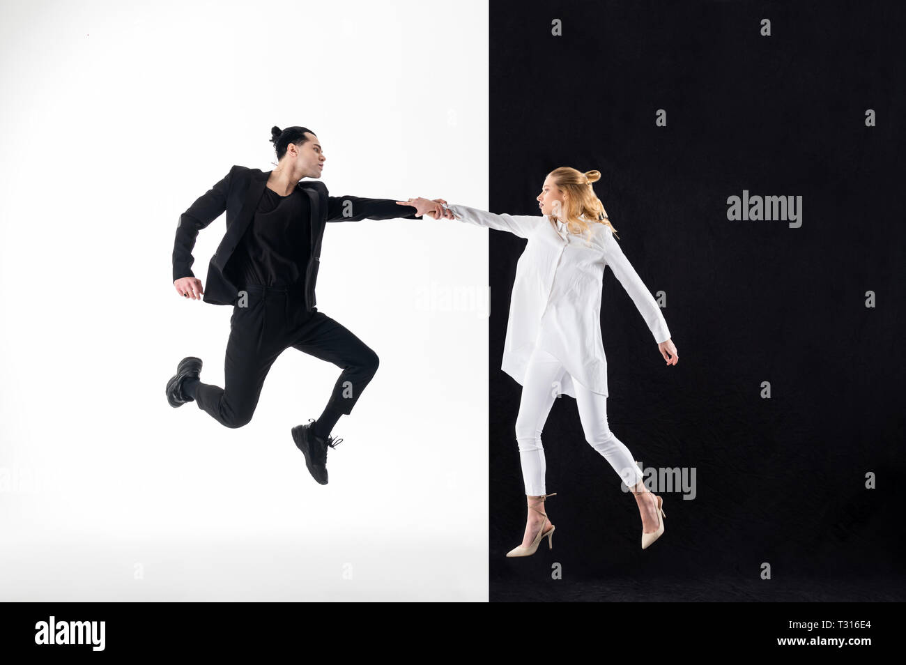 Tenant la main. Blonde model wearing long chemisier blanc tenant la main de son collègue en costume noir Banque D'Images