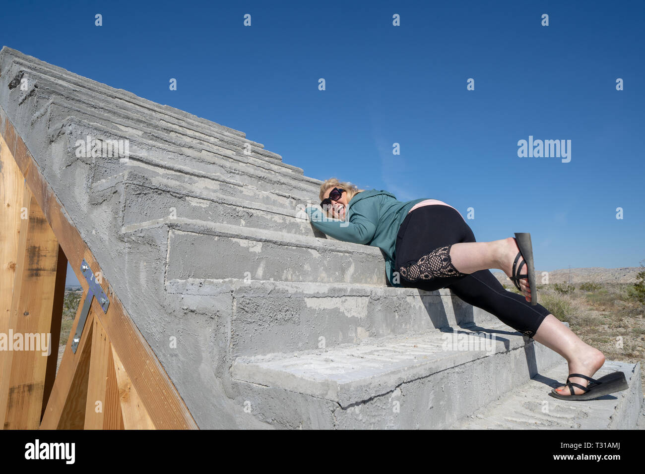 Terrifié femme blonde tente de ramper jusqu'à l'extérieur un escalier en béton Banque D'Images