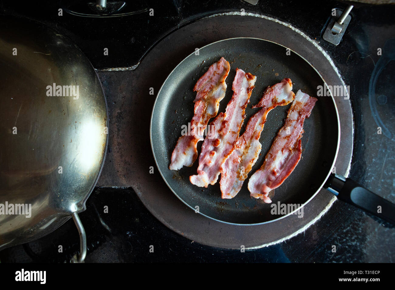 Faire frire le bacon pour le petit déjeuner Banque D'Images