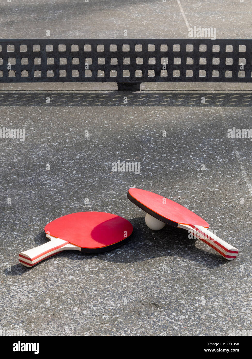 Deux raquettes de tennis de table allongé sur une table de ping-pong en béton. Aire de l'objet, la lumière du soleil. Active dans l'air libre. Banque D'Images