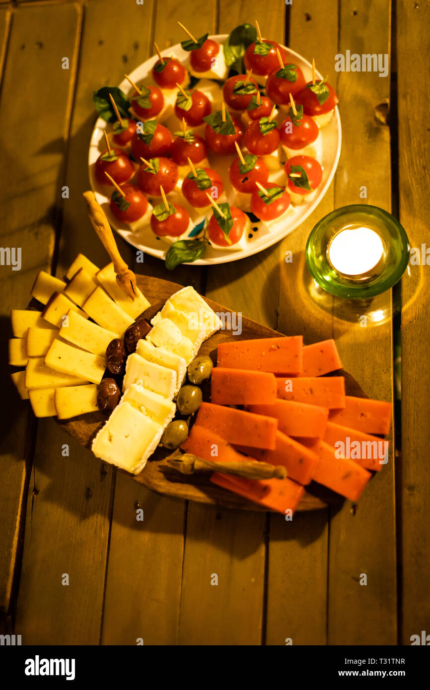 Plateau de fromages faits maison aux olives, mozarela, tomates et basilic frais bébé plus de chandelles. Banque D'Images