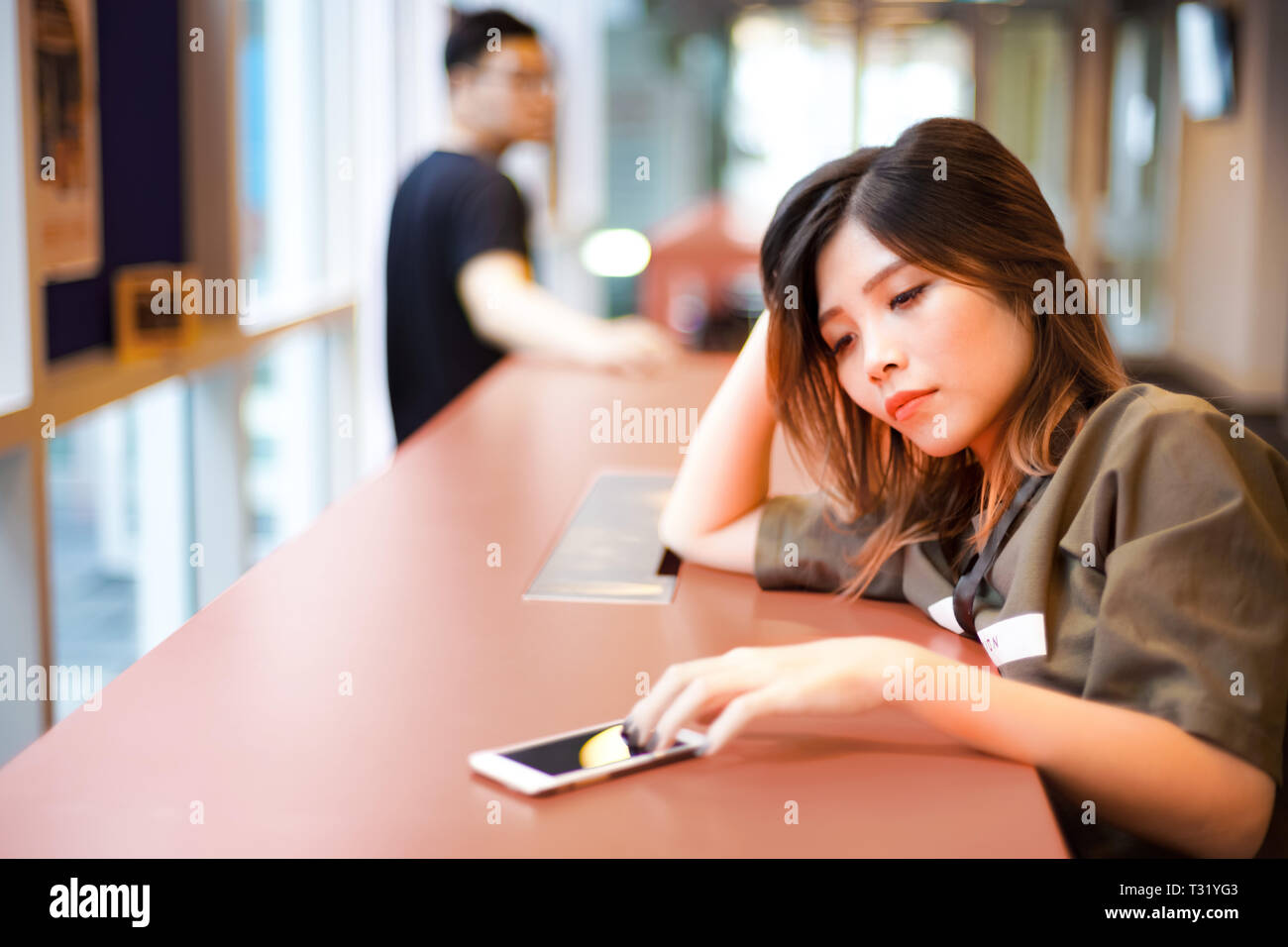 Lonely sad girl en attente de message texte de smartphone sur la table | Couple séparés les uns des autres Banque D'Images