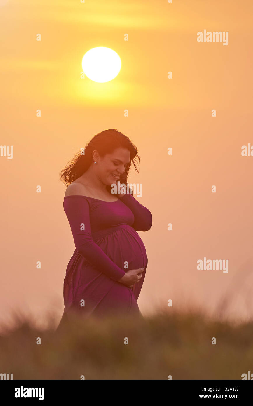 Femme enceinte sur lumière ensoleillée position sur fond de ciel clair Banque D'Images