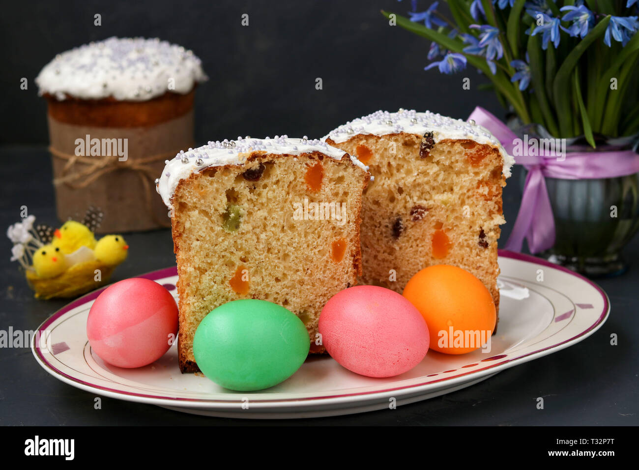 Gâteaux de Pâques et les oeufs colorés sont situés sur une plaque sur un fond sombre Banque D'Images