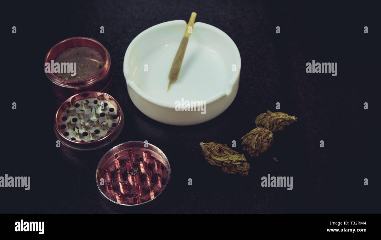 Fumer de la marijuana médicale. Bourgeons de marijuana, broyeur et le cendrier sur l'arrière-plan. Main de femme dans la commune Banque D'Images
