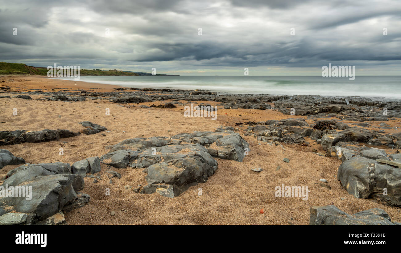 Nuages sombres et les grosses pierres, vu à Cocklawburn Beach près de Berwick-upon-Tweed dans le Northumberland, England, UK Banque D'Images
