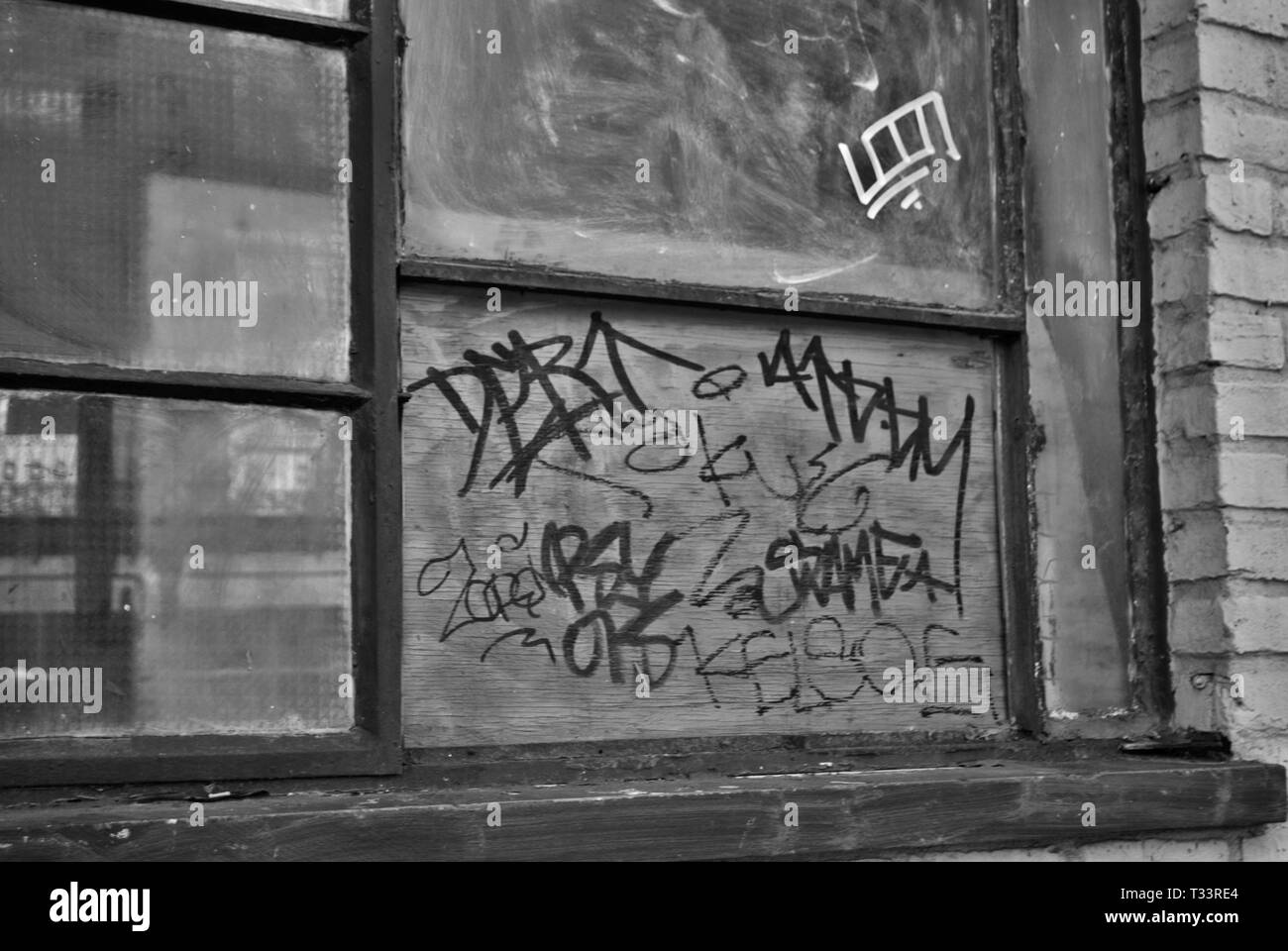 Close up of a broken barricadèrent fenêtre et l'appui avec l'écaillage de la peinture et graffiti Banque D'Images