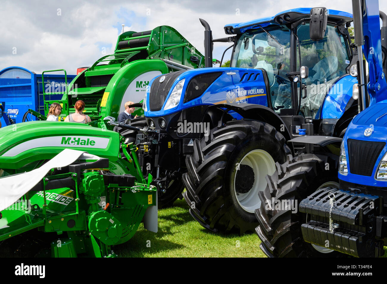 Affichage des machines agricoles (tracteurs New Holland, McHale ramasseuse-presse & tondeuse) garés côte à côte sur le commerce stand - Great Yorkshire Show, England, UK. Banque D'Images