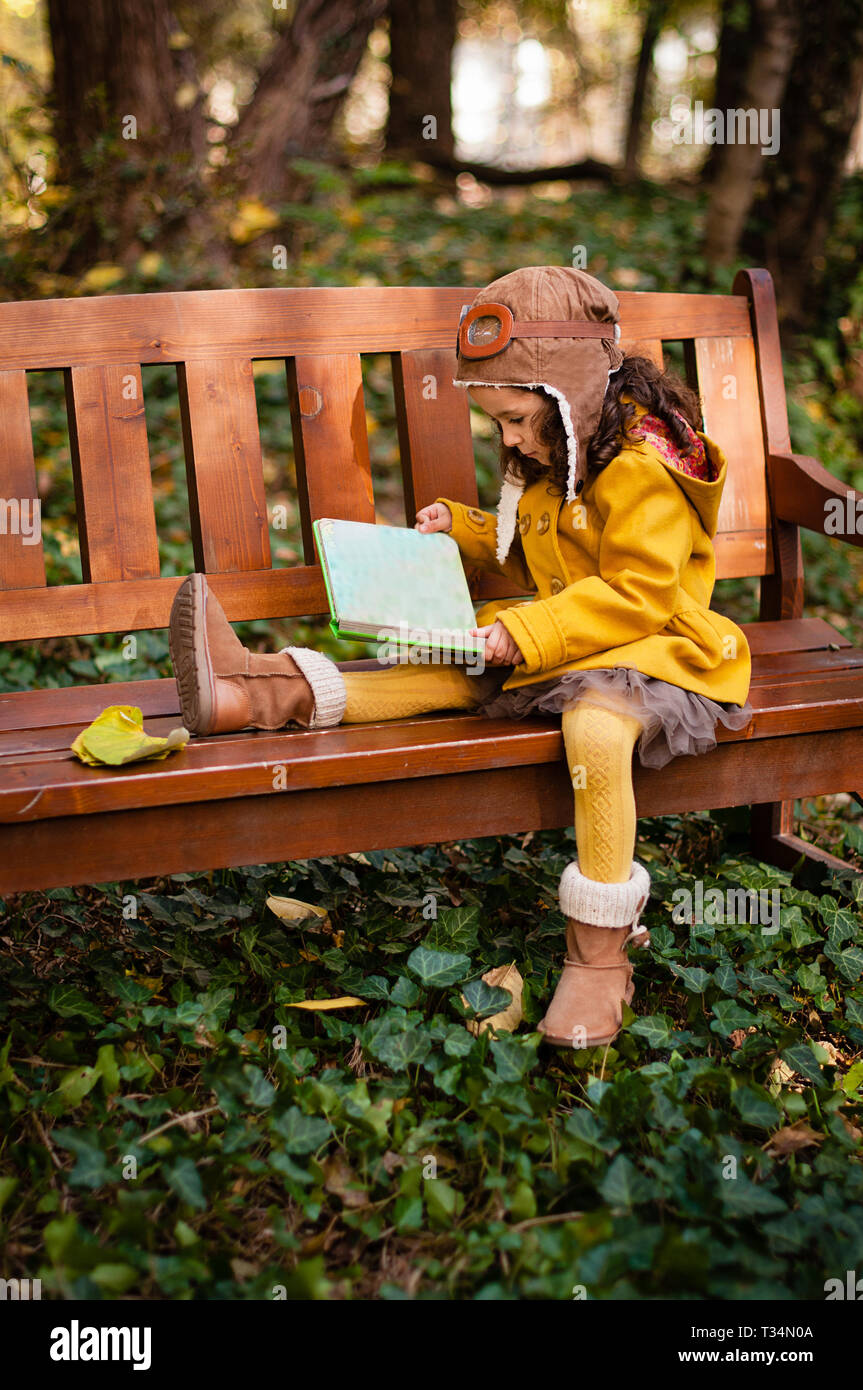 Jeune fille portant un chapeau et des lunettes aviateur assis sur un banc, lisant un livre, en Bulgarie Banque D'Images