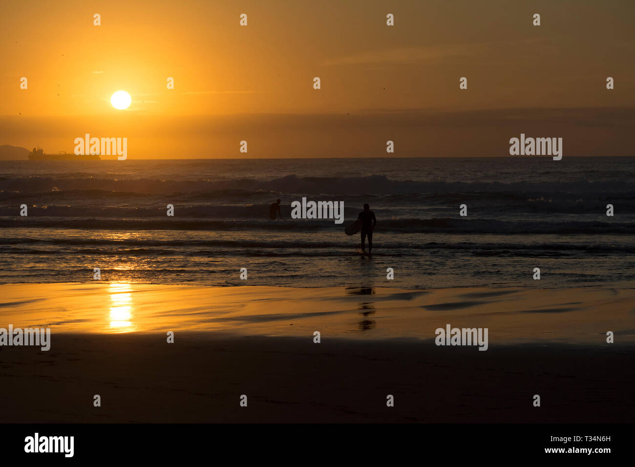 Deux surfeurs sur la plage au coucher du soleil, plage de Sopelana, Biscaye, Espagne Banque D'Images