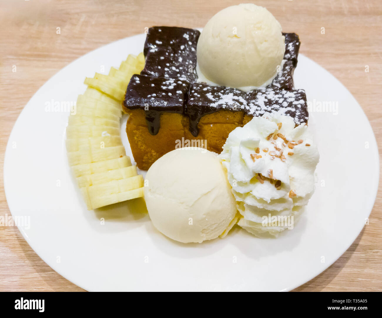 Toast au miel et à la vanille avec de la glace à la crème à fouetter et tranche de banane sur la table en bois dans le dessert cafe. Banque D'Images