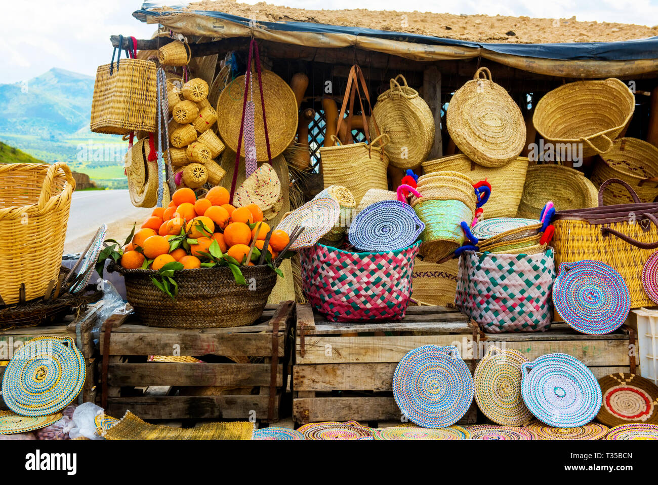 Chapeaux en osier artisanat, les oranges et autres souvenirs dans le marché du Maroc Banque D'Images